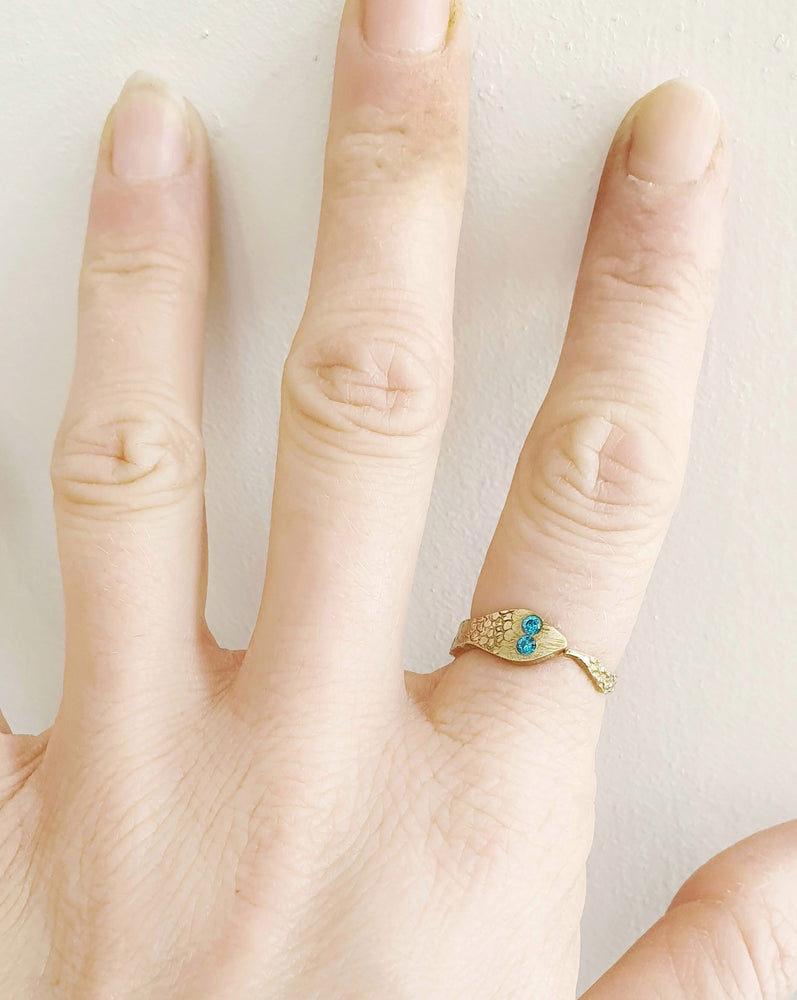 Crafted with a snake-shaped design and textured brass, the ring stands out with its 2mm blue zircons and adjustable fit.