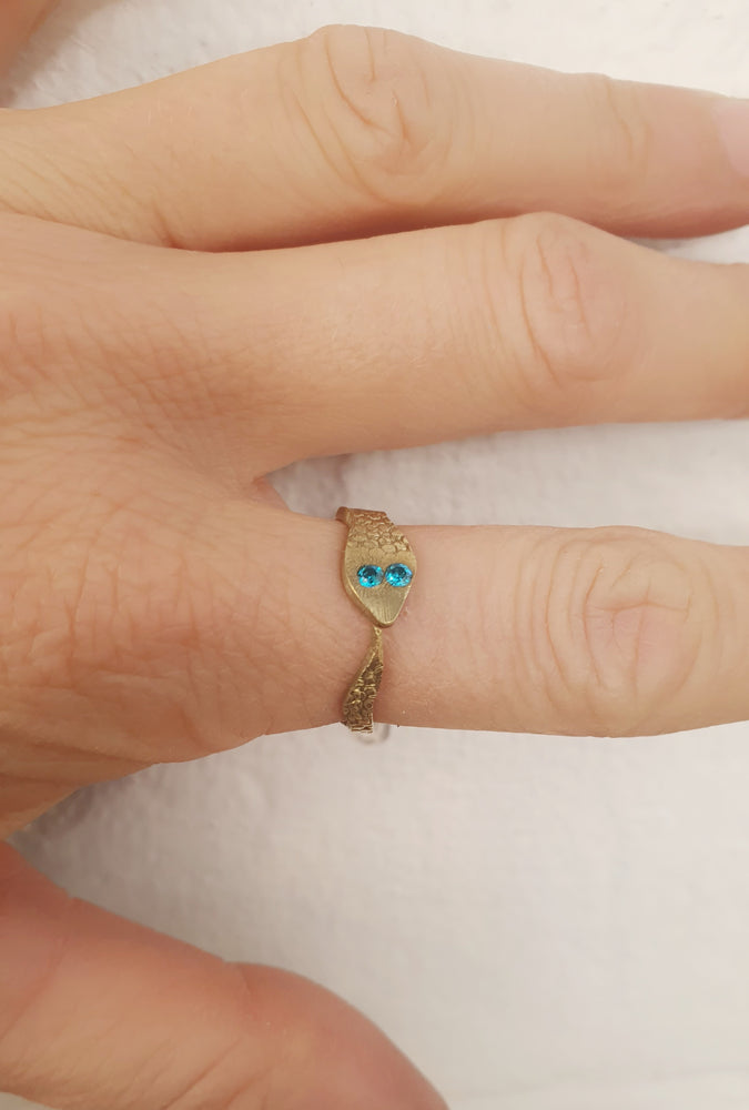 Crafted with a snake-shaped design and textured brass, the ring stands out with its 2mm blue zircons and adjustable fit.