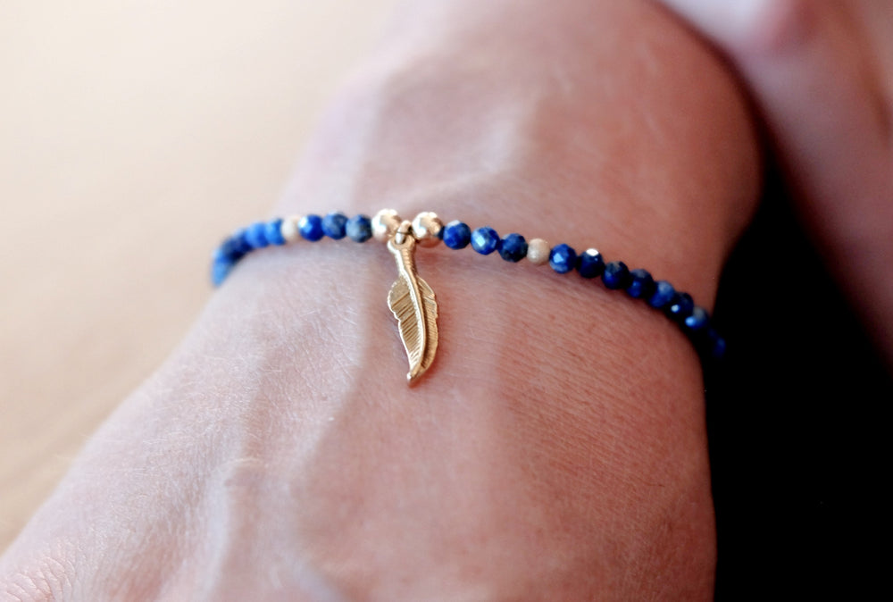 
            
                Load image into Gallery viewer, Made with 3mm natural semi-precious Lapis Lazuli gemstones and high quality hypoallergenic surgical steel and 14k gold filled beads and a little surgical steel feather charm
            
        