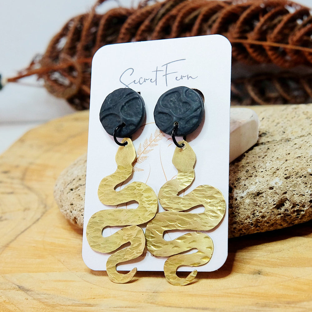 textured brass snake earring 5.5cm long with a black textured polymer clay stud