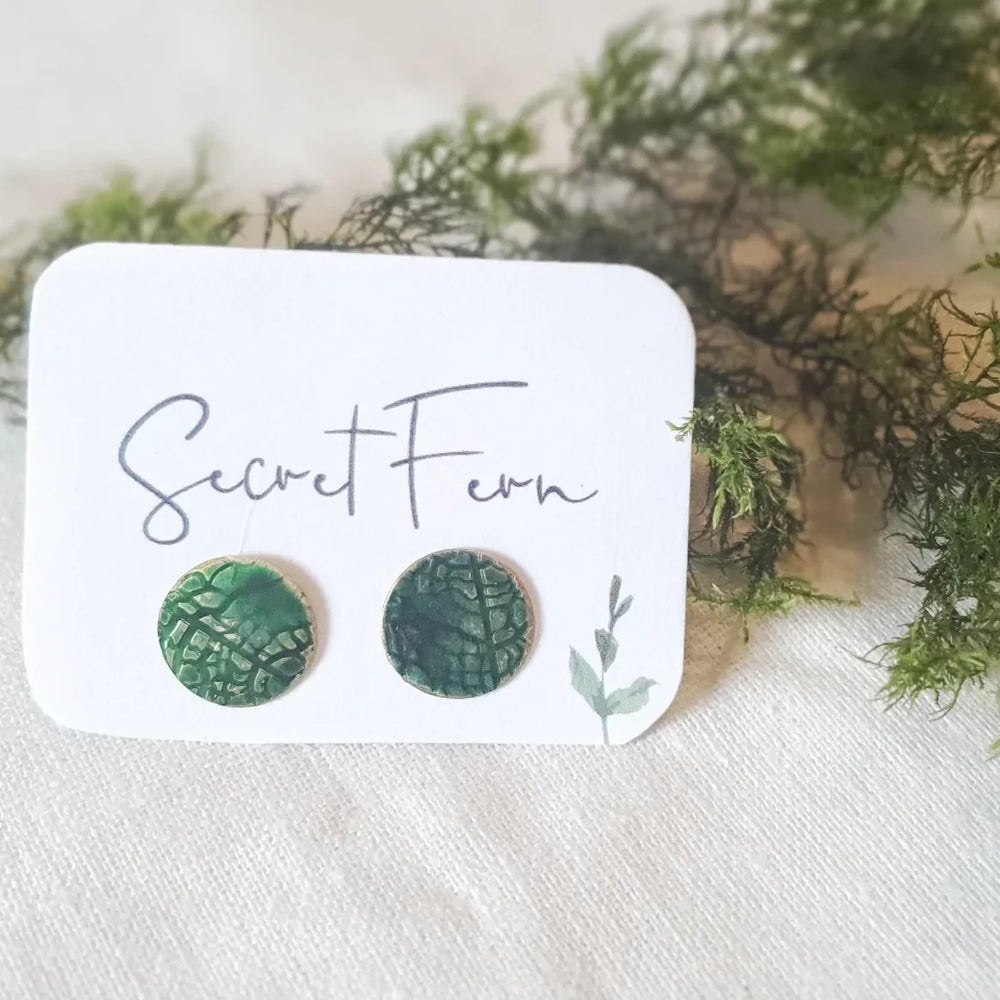 1.3cm round brass disc with leaf imprint and hand-painted in green then sealed. With Sterling silver posts. 