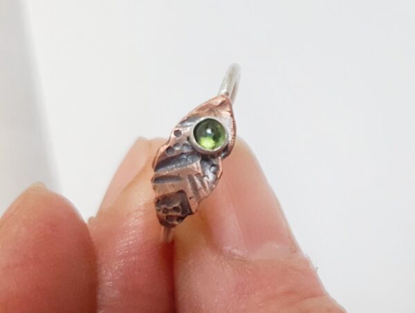 This beautiful Tribal Tourmaline Ring features a 3mm natural green tourmaline gemstone surrounded by a dainty silver band and copper leaf-shaped design.