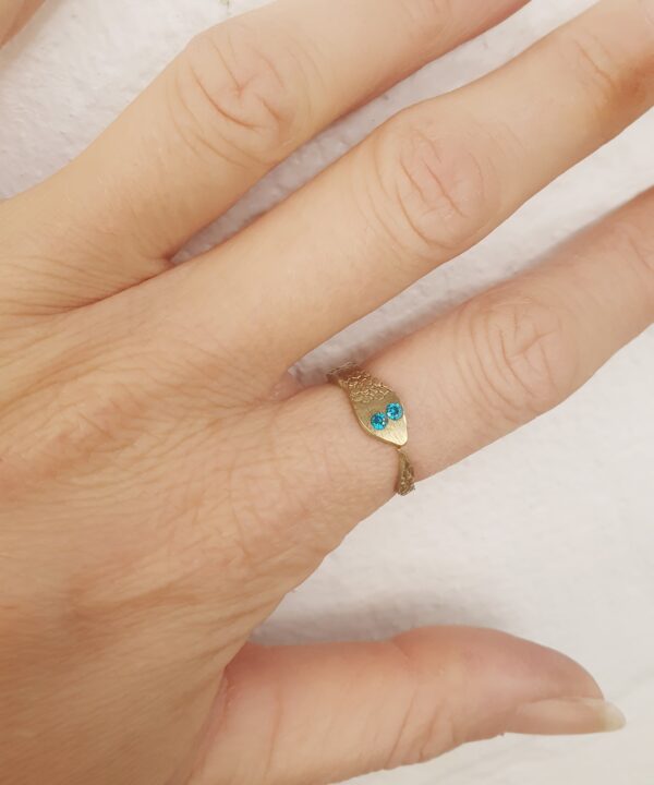 Crafted with a snake-shaped design and textured brass, the ring stands out with its 2mm blue zircons and adjustable fit.
