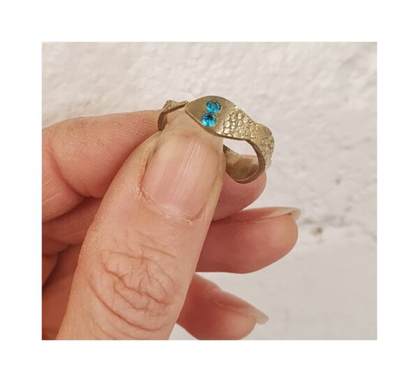 Crafted with a snake-shaped design and textured brass, the ring stands out with its 2mm blue zircons and adjustable fit.